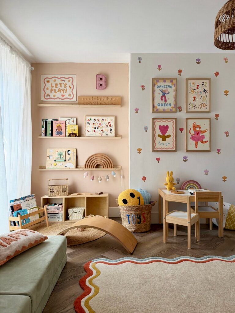 Children's playroom with wooden furniture, colorful wall decals, and framed art on shelves and walls.